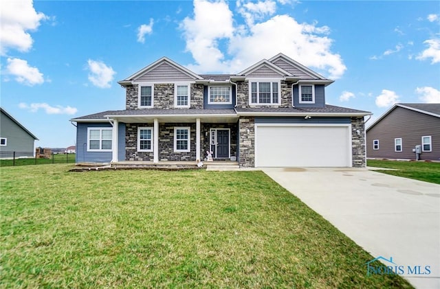 view of front facade with a front lawn, fence, stone siding, and a garage