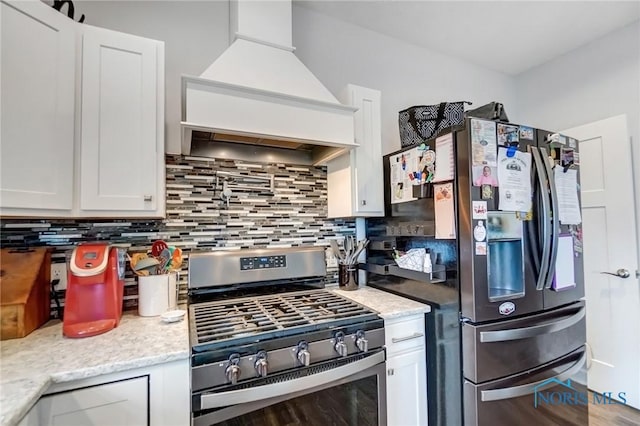 kitchen with decorative backsplash, white cabinetry, custom range hood, and appliances with stainless steel finishes