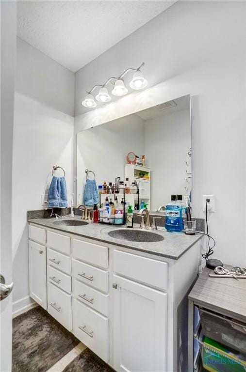 full bathroom featuring double vanity, baseboards, and a sink