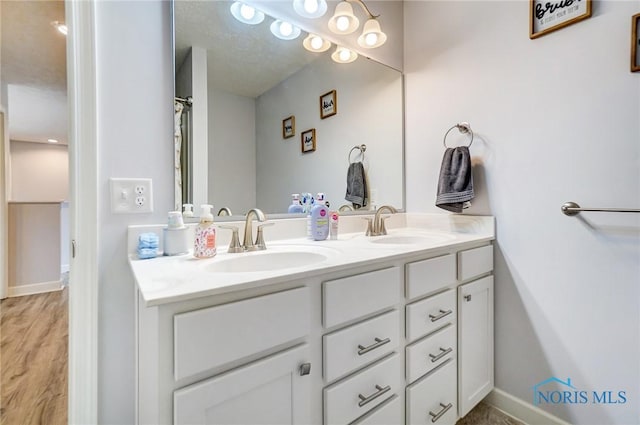 bathroom featuring double vanity, a sink, and baseboards