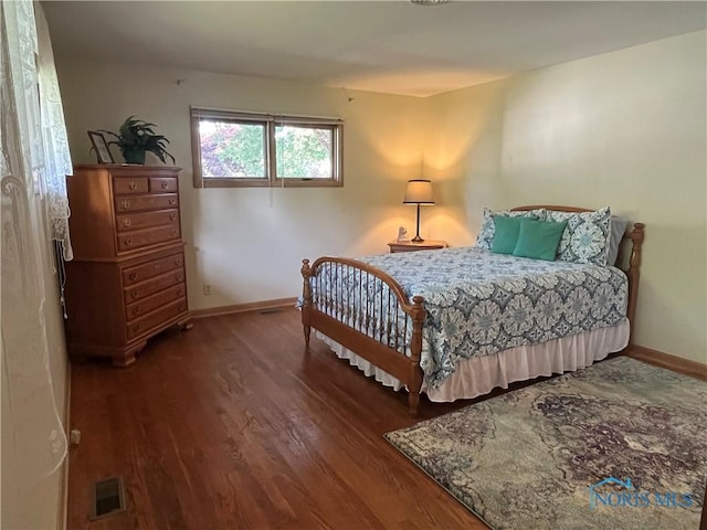bedroom with baseboards, visible vents, and wood finished floors