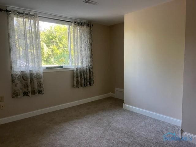 spare room featuring baseboards, carpet flooring, and visible vents