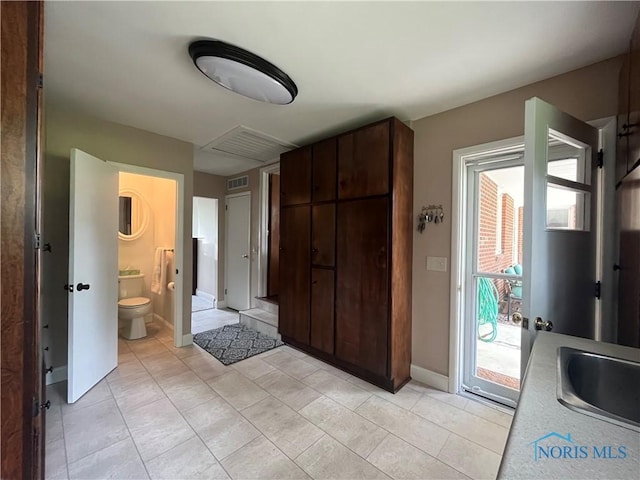 interior space with tile patterned floors, toilet, a sink, baseboards, and visible vents