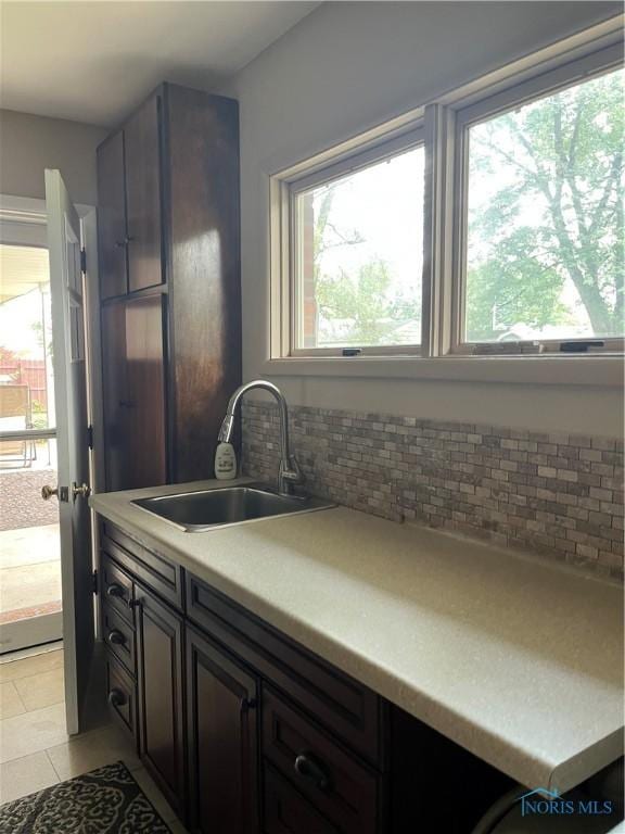 kitchen with decorative backsplash, a sink, light tile patterned floors, and plenty of natural light