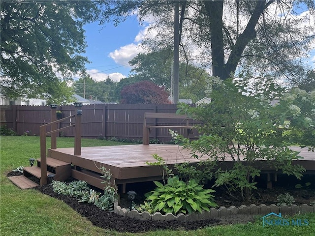 wooden terrace featuring a yard and fence