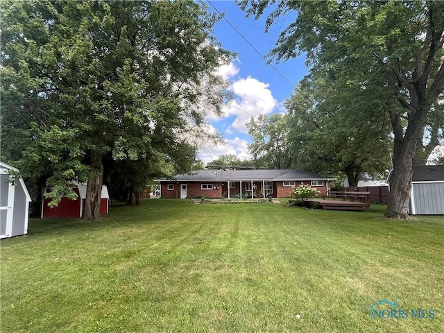 view of yard featuring a wooden deck, an outbuilding, and a storage shed