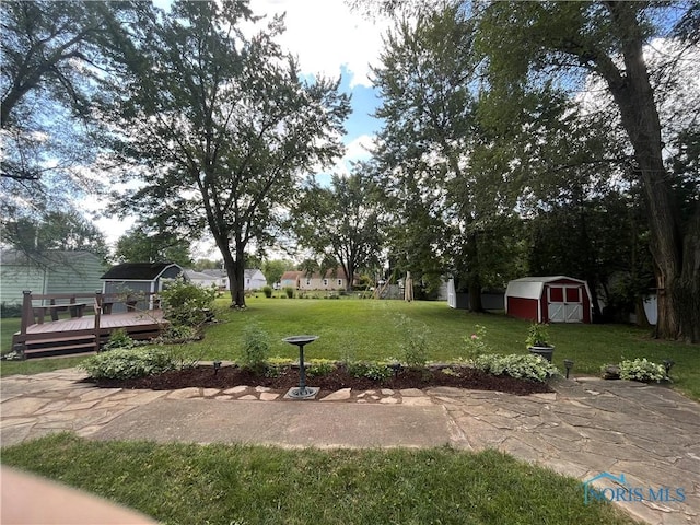 view of yard featuring an outbuilding, a shed, and a deck