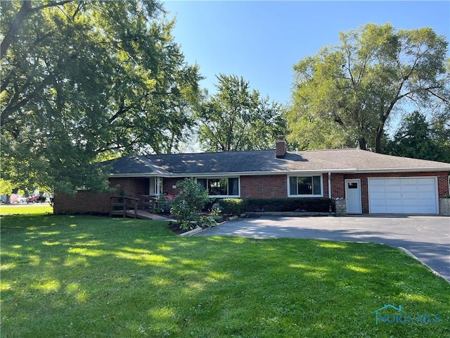 ranch-style home with a chimney, brick siding, an attached garage, and a front lawn