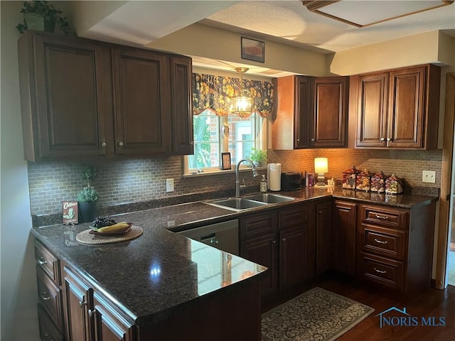 kitchen featuring decorative backsplash, dark stone counters, a sink, dark wood-style floors, and dishwashing machine