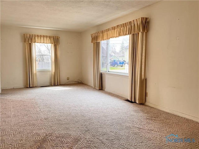 carpeted spare room with baseboards and a textured ceiling