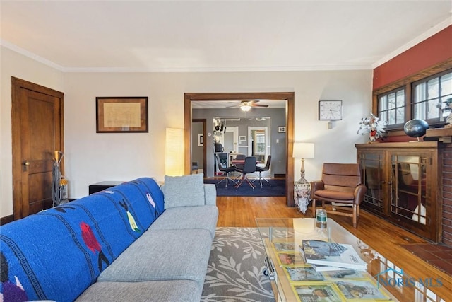 living room with ornamental molding, a ceiling fan, and wood finished floors