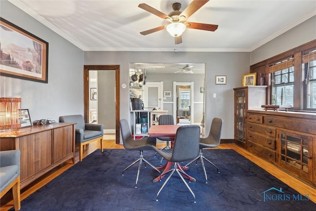 dining room featuring baseboards, a ceiling fan, crown molding, and wood finished floors