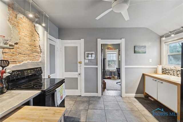 kitchen with black electric range, a sink, ceiling fan, tile patterned floors, and lofted ceiling
