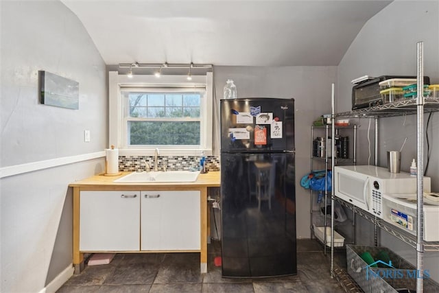 interior space featuring a sink, backsplash, rail lighting, and vaulted ceiling