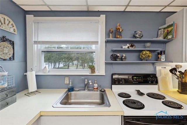 kitchen with light countertops, a paneled ceiling, a sink, and electric range oven