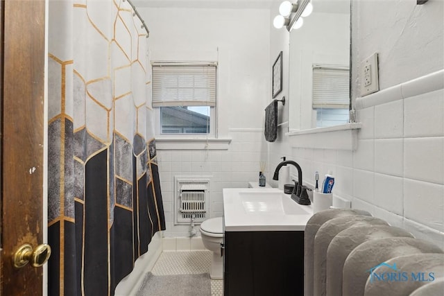 full bathroom featuring vanity, toilet, a shower with shower curtain, tile walls, and heating unit