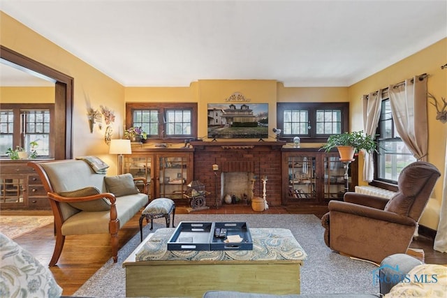 living area featuring a brick fireplace and wood finished floors