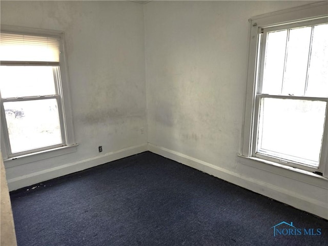 empty room with plenty of natural light, baseboards, and dark carpet