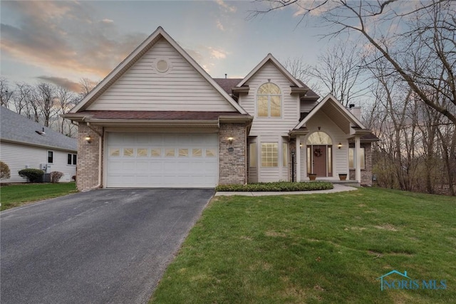 2016 Austin Bluffs Ct, Toledo, OH 43615 - view of front of home with brick siding, aphalt driveway, an attached garage, and a lawn
