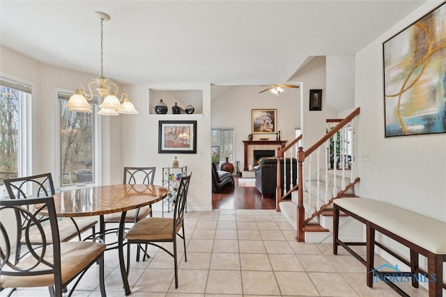 2016 Austin Bluffs Ct, Toledo, OH 43615 - dining room featuring stairs, a tiled fireplace, ceiling fan with notable chandelier, and light tile patterned flooring