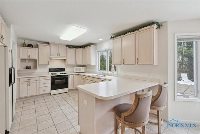 2016 Austin Bluffs Ct, Toledo, OH 43615 - kitchen featuring light tile patterned floors, light countertops, white appliances, a peninsula, and a breakfast bar area