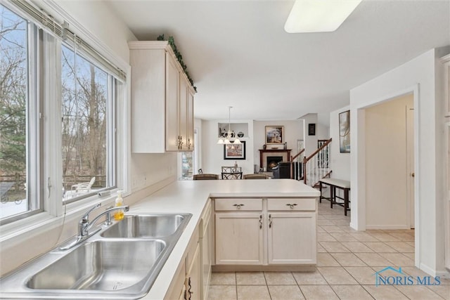 2016 Austin Bluffs Ct, Toledo, OH 43615 - kitchen featuring a peninsula, light tile patterned floors, light countertops, a sink, and hanging light fixtures