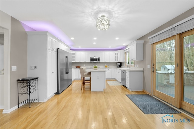 kitchen with white cabinetry, stainless steel appliances, a breakfast bar, a sink, and light wood-style floors