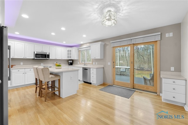 kitchen with white cabinetry, light wood-style flooring, a breakfast bar, and appliances with stainless steel finishes