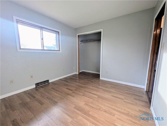 unfurnished bedroom featuring a closet, baseboards, light wood-style floors, and visible vents