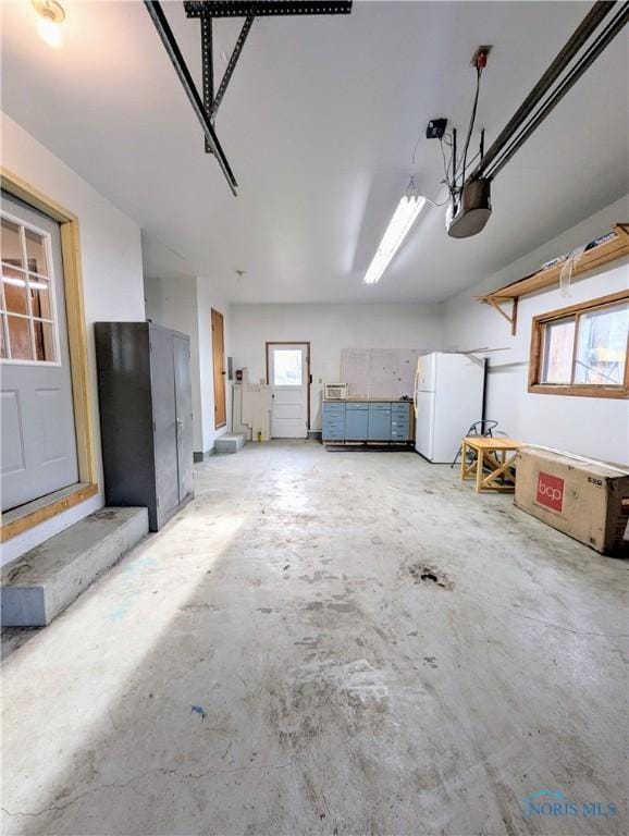 garage featuring a garage door opener and freestanding refrigerator