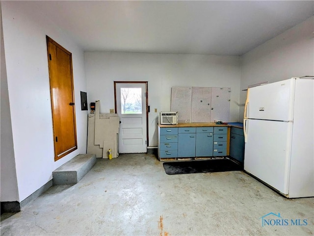 kitchen featuring freestanding refrigerator, concrete flooring, and butcher block counters