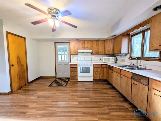 kitchen with white appliances, light countertops, wood finished floors, and a sink