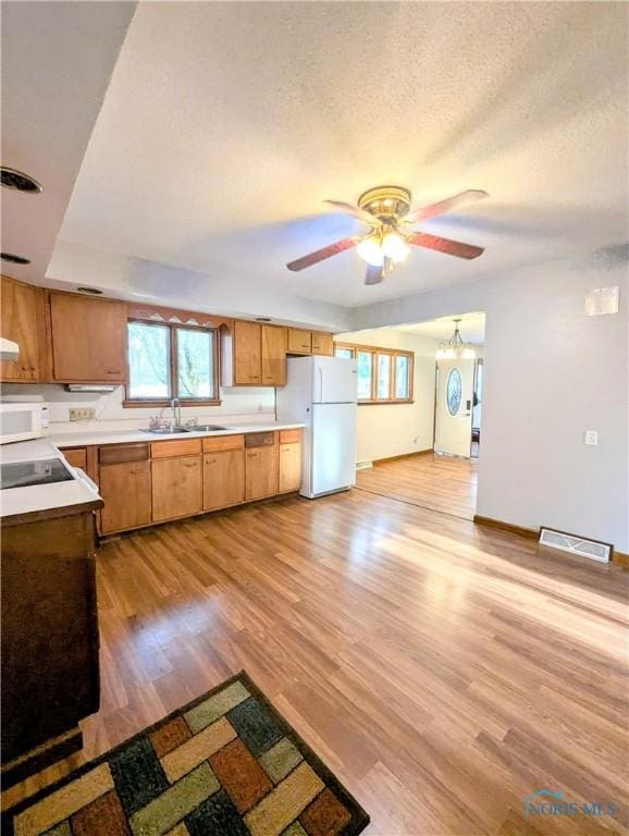 kitchen with light countertops, light wood-type flooring, white appliances, a sink, and a ceiling fan