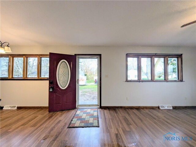 entryway featuring baseboards, visible vents, and wood finished floors