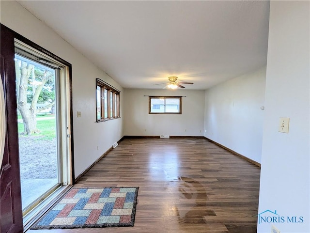 spare room featuring a ceiling fan, visible vents, baseboards, and wood finished floors