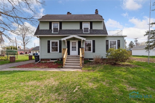 view of front of home with a front yard, a shingled roof, and a chimney