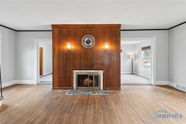 unfurnished living room featuring wood finished floors, baseboards, and crown molding