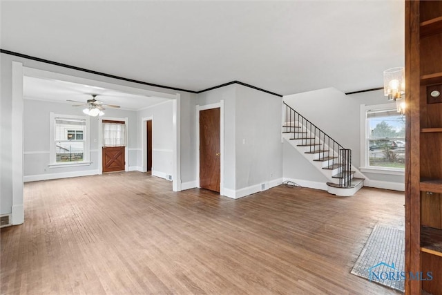 unfurnished living room featuring baseboards, wood finished floors, and a wealth of natural light