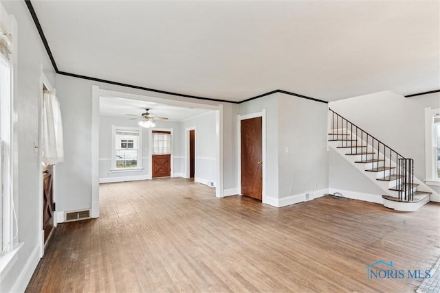 unfurnished living room featuring visible vents, baseboards, wood finished floors, ceiling fan, and ornamental molding