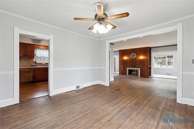 unfurnished living room featuring a warm lit fireplace, plenty of natural light, visible vents, and wood finished floors