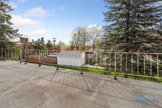 view of patio / terrace with fence, a storage unit, and an outbuilding