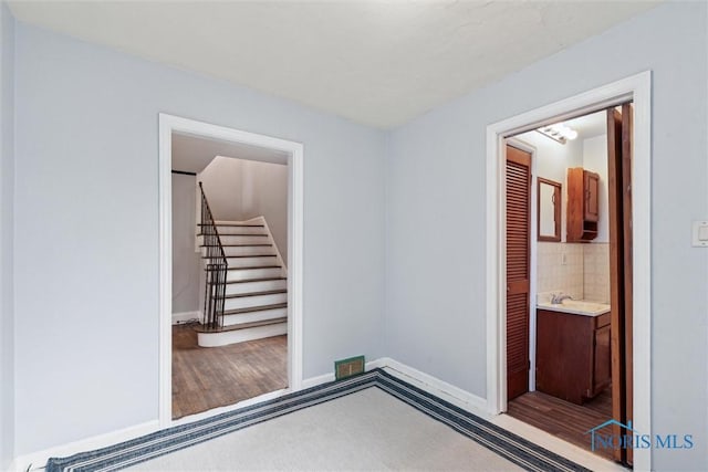 interior space with a sink, connected bathroom, carpet floors, baseboards, and visible vents