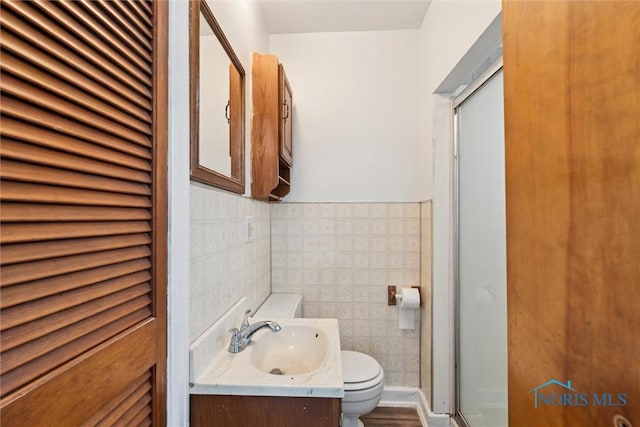 bathroom featuring a shower stall, tile walls, toilet, and vanity