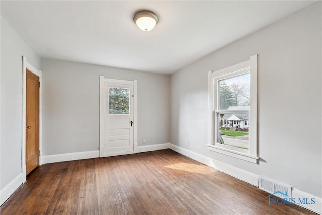unfurnished room with baseboards, hardwood / wood-style flooring, and visible vents