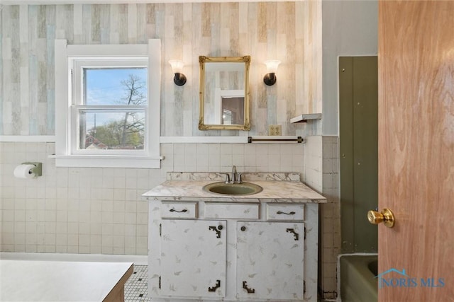 bathroom featuring a tub to relax in, vanity, and tile walls
