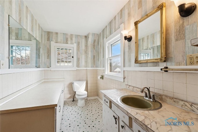 bathroom featuring toilet, wallpapered walls, and tile walls