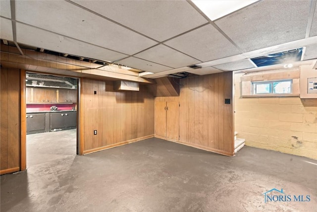 below grade area with wood walls and a drop ceiling