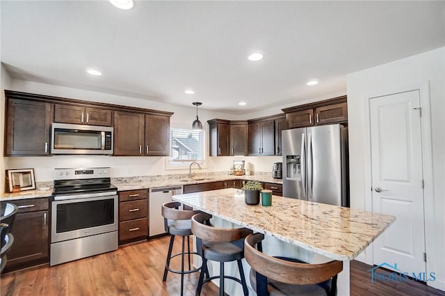 630 Weatherby Ct, Findlay, OH 45840 - kitchen with a breakfast bar area, stainless steel appliances, light wood-style floors, light stone counters, and dark brown cabinetry