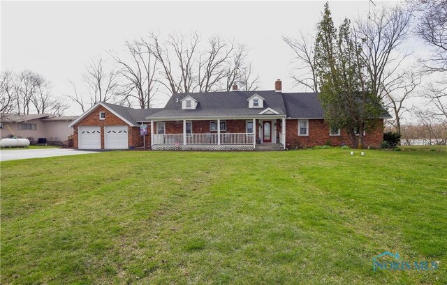 cape cod home featuring a front yard, brick siding, a porch, and driveway