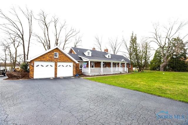 view of front of property featuring a front yard, brick siding, a porch, a garage, and a chimney